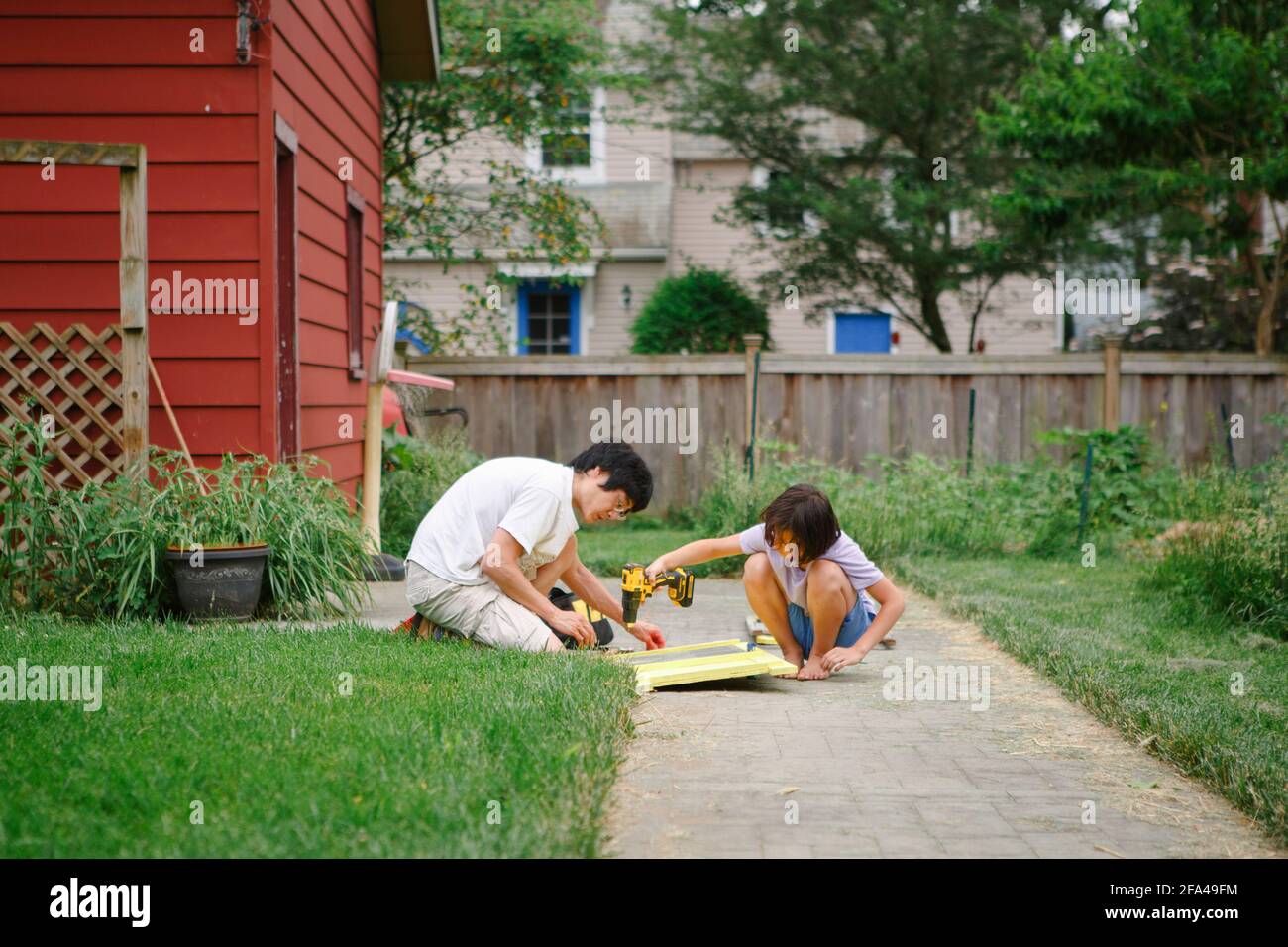 Ein Sohn und ein Vater bauen zusammen mit einem elektrischen Bohrer ein Hinterhof Stockfoto