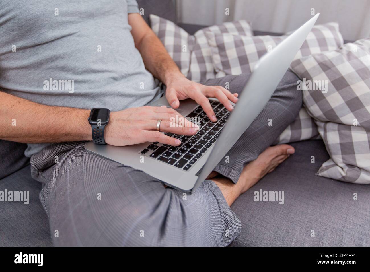 Der Mann arbeitet für Laptops, die in Nahaufnahme auf den Couchhänden sitzen Stockfoto