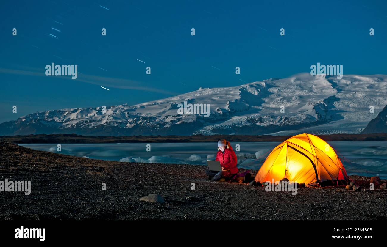 Die Wissenschaftlerin sitzt mit einem Laptop außerhalb ihres Zeltes in der Arktis Klima Stockfoto
