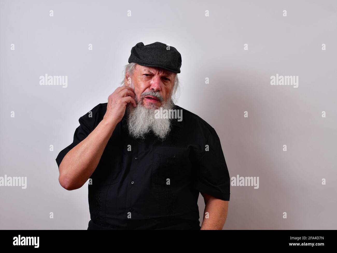 Ein älterer Mann, der tief in Gedanken an seinem Bart kratzt Stockfoto