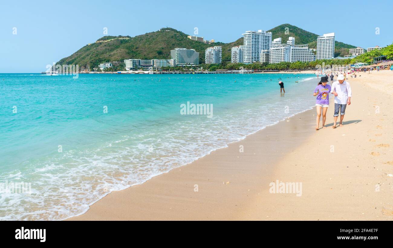 Sanya China , 25. März 2021 : Chinesische Touristen gehen barfuß am weißen Sandstrand von Dadonghai an einem sonnigen Tag auf der Insel Sanya Hainan China Stockfoto