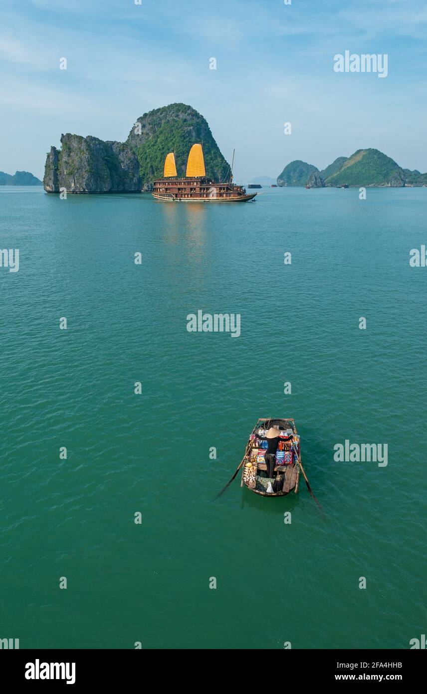 Verkäuferin auf einem Boot mit Kreuzfahrtboot, Halong Bay, Vietnam. Stockfoto