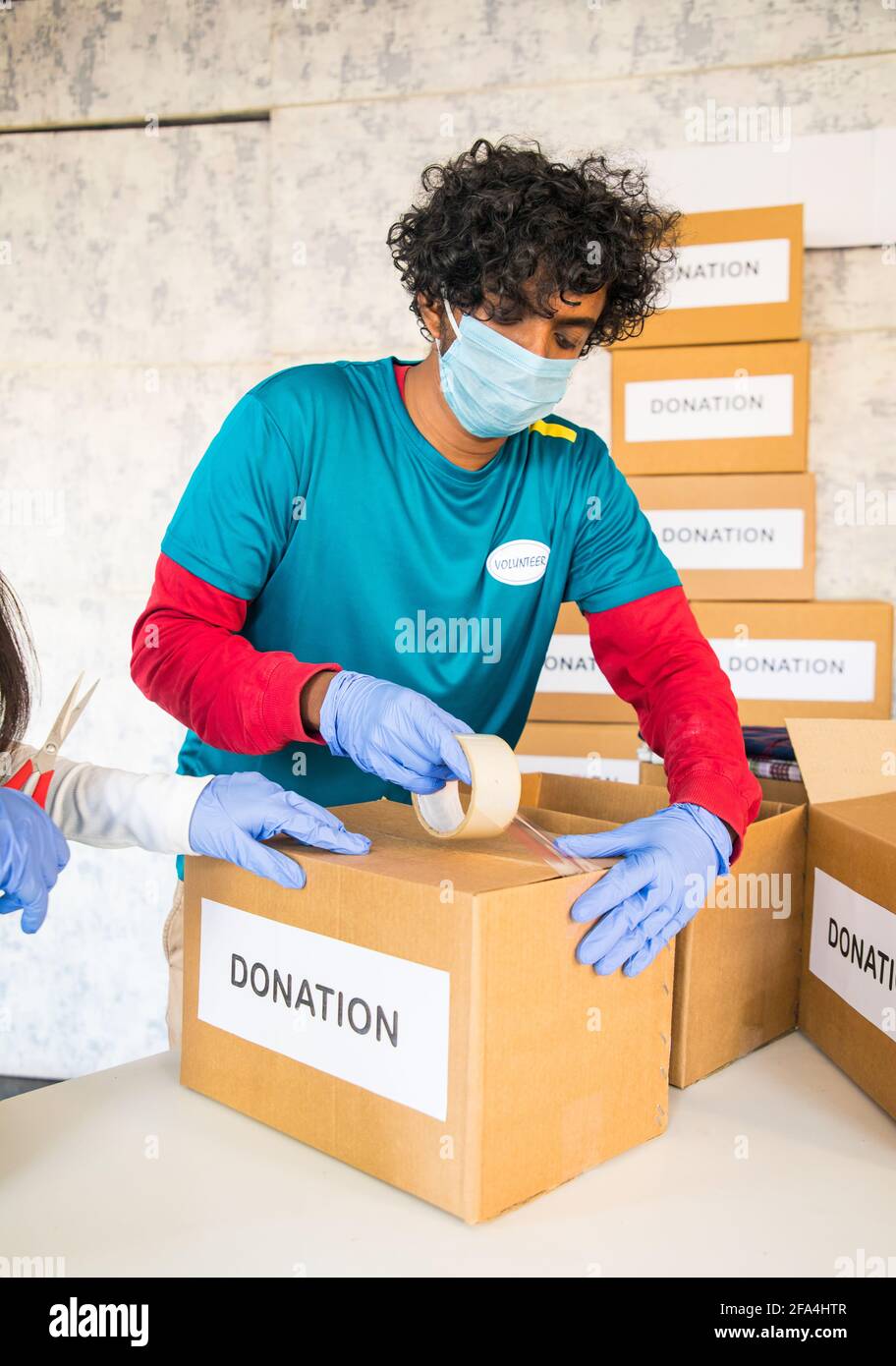 Freiwillige beschäftigt Verpackung Spenden-Boxen für Spenden - Konzept der Wohltätigkeit, Sozialarbeit oder Dienst während Coronavirus covid-19 Pandemie Sperrung. Stockfoto