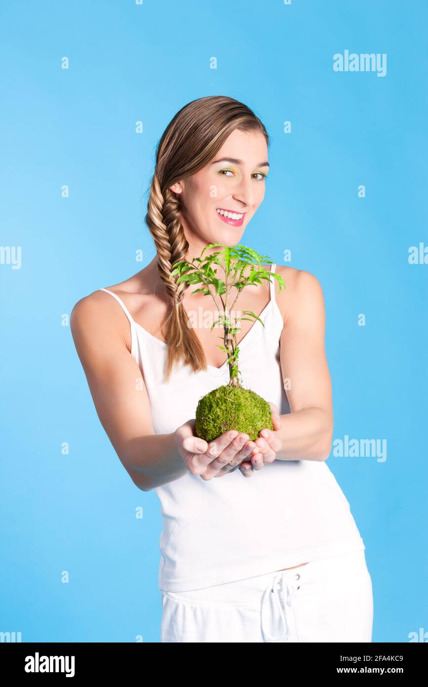 Junge Frau mit symbolisch einen kleinen Baum, ein Symbol für den Schutz und die Pflege unserer Umwelt, Wald und Welt Stockfoto