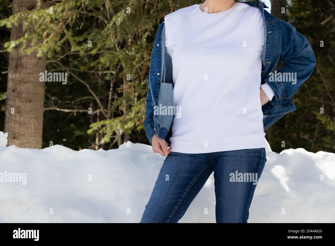 Weißes Fleece-Sweatshirt mit Rundhalsausschnitt und einem Mädchen im verschneiten Winterwald. Schwere Sweatshirt Vorlage, Modell Mockup Stockfoto