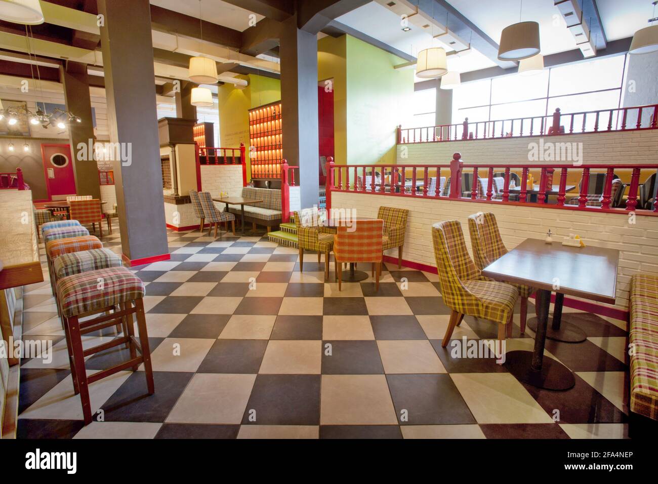 Dekorative Stühle und Tische in einer stilvollen Cafeteria mit farbenfrohen Farben Wände und moderne Lampen Stockfoto