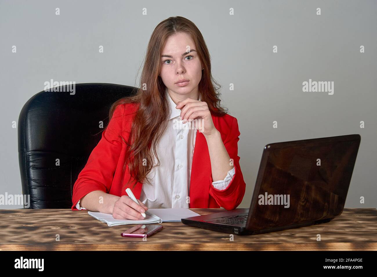 Eine Frau, die an einem Schreibtisch sitzt und mit einem Laptop arbeitet Und Notizblock Stockfoto