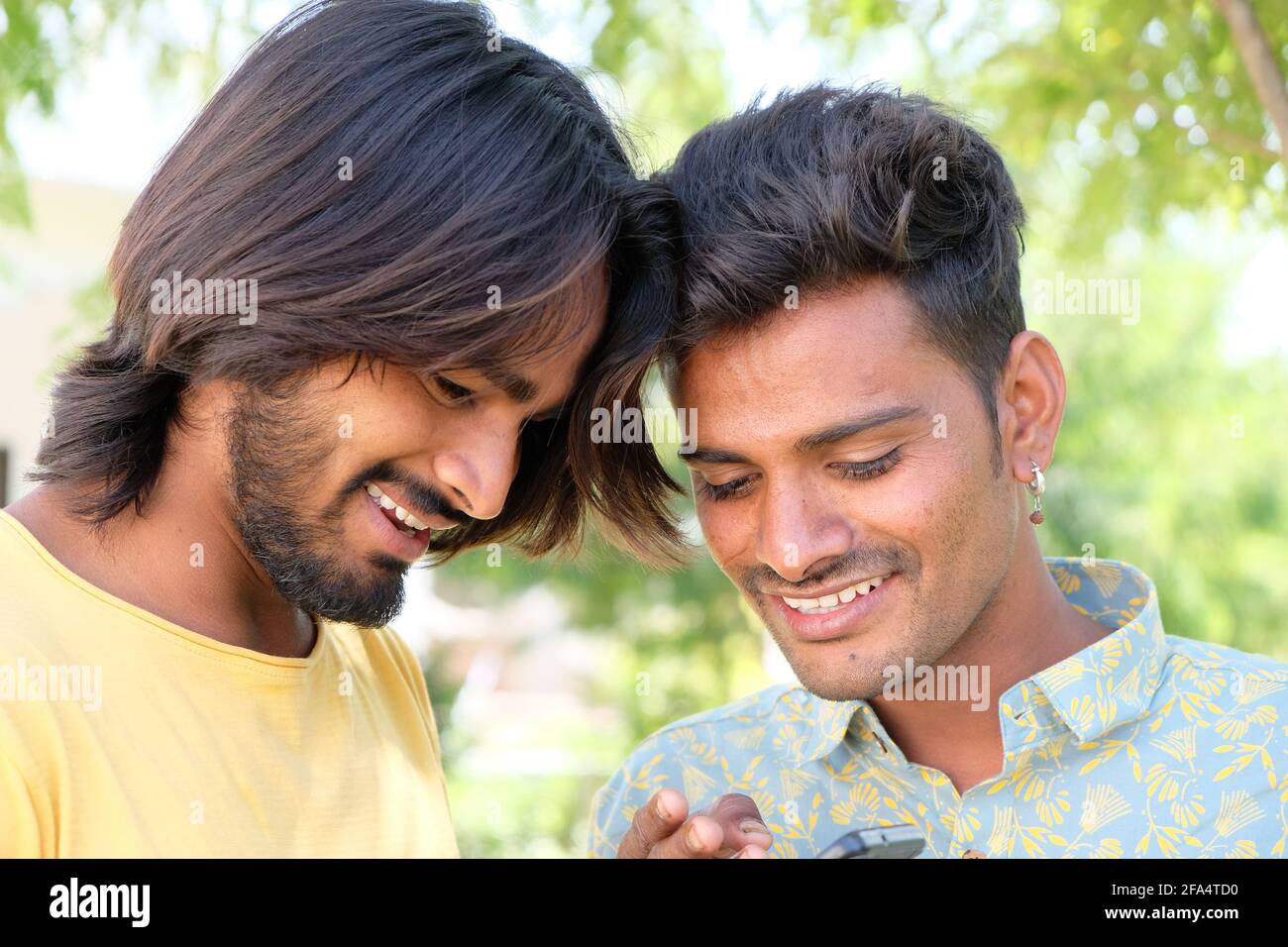 Glücklich jung indisch Gay Paar Blick auf ihre Fotos auf Das Telefon im  Freien Stockfotografie - Alamy