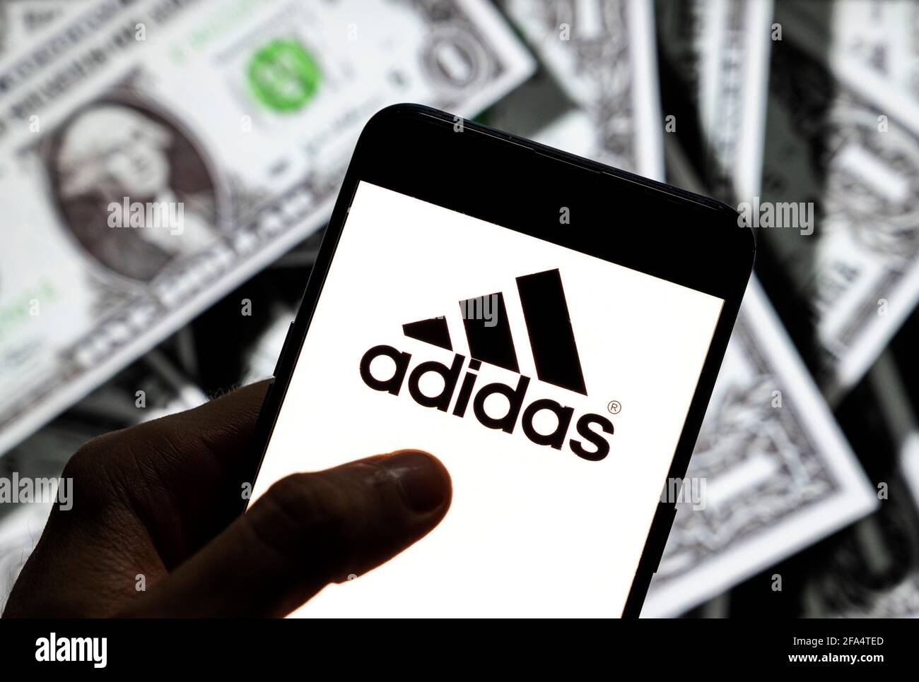 In dieser Fototafel ist das deutsche multinationale Sportbekleidungslogo  der Marke Adidas auf einem Android-Handy-Bildschirm mit der Währung des  US-Dollar-Symbols, dem Dollar-Symbol im Hintergrund, zu sehen  Stockfotografie - Alamy