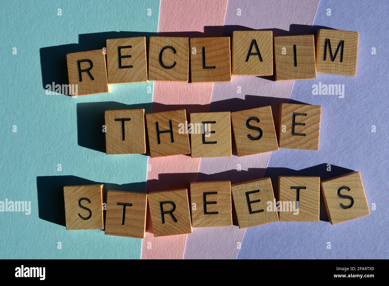 Erobern Sie diese Straßen zurück, Wörter in hölzernen Buchstaben, die auf pastellfarbenem Hintergrund isoliert sind Stockfoto