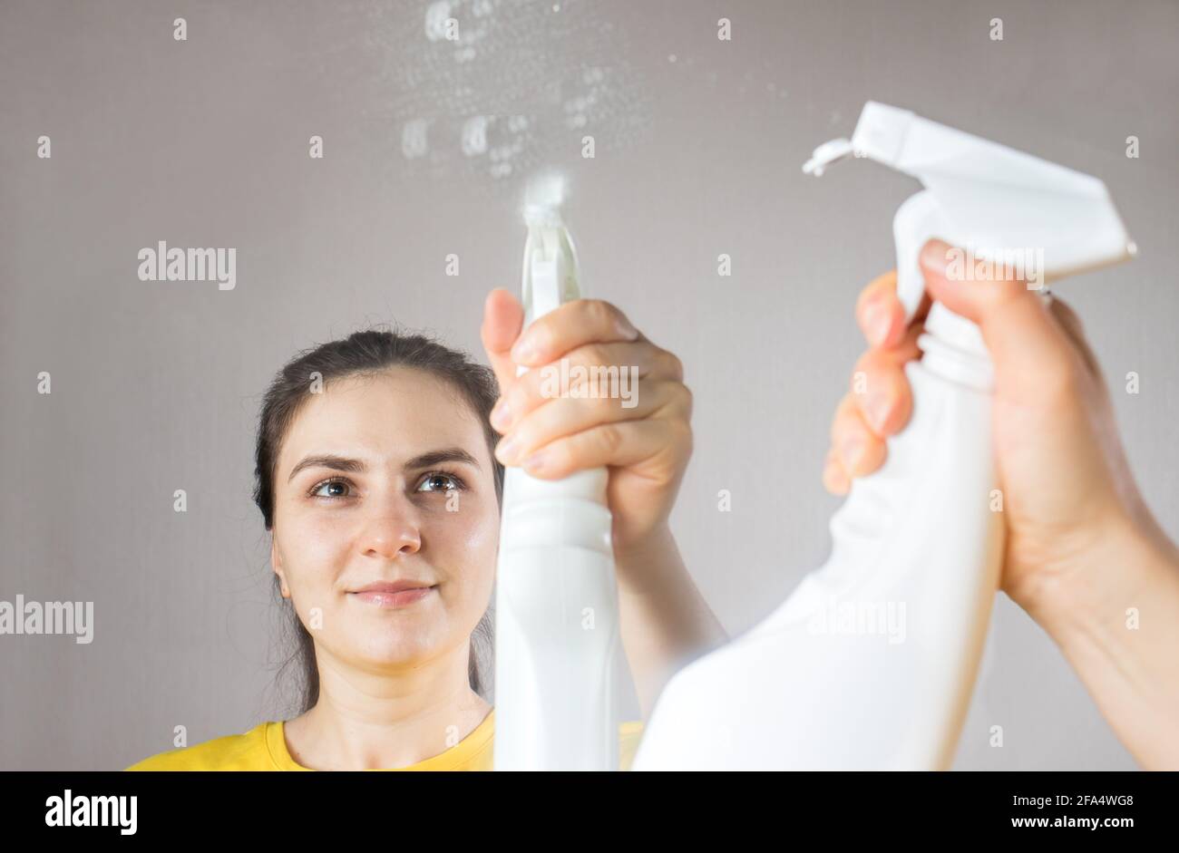 Die Putzfrau reinigt den Spiegel mit einem Wasserspender und Fensterreiniger. Hausreinigung. Reinigungsservice Stockfoto