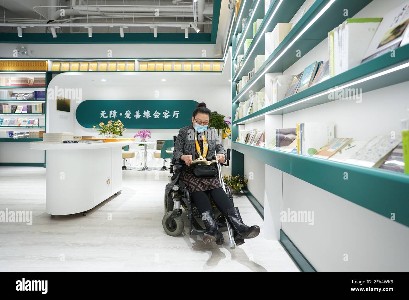 (210423) -- PEKING, 23. April 2021 (Xinhua) -- der behinderte Autor Luo Yan durchsucht ein Buch in der Shanyuan-Buchkammer in Peking, der Hauptstadt Chinas, am 14. April 2021. In der Shanyuan Book Chamber, einer barrierefreien Buchhandlung, berücksichtigt jedes Design und Layout die Bedürfnisse behinderter Leser. Die Buchhandlung erstreckt sich über eine Fläche von über 300 Quadratmetern im Bezirk Dongcheng in Peking und bietet Bücherregale mit alternativen Höhen, Möbel mit abgerundeter Kante, ausreichend Platz für Rollstühle und andere Einrichtungen, um die Zugänglichkeit zu verbessern. Darüber hinaus legt die Buchhandlung viel Wert auf die Werke von au Stockfoto