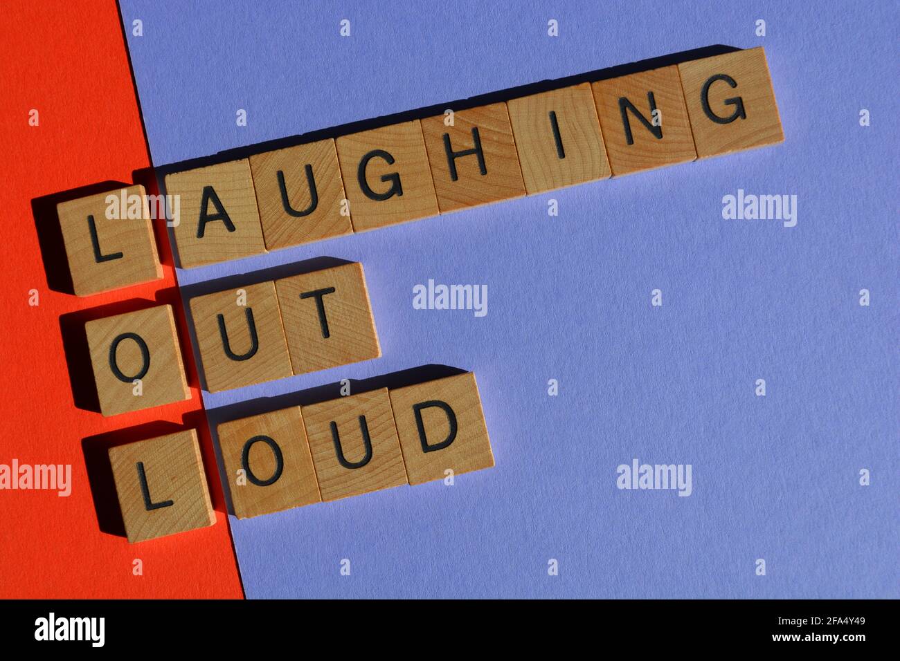 LOL, Akronym für lautes Lachen in hölzernen Buchstaben, isoliert auf buntem Hintergrund Stockfoto