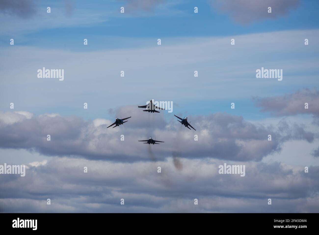 Vier Düsenflugzeuge fliegen in enger Formation. Gefährliche Kunstflüge werden auf dem Luftfahrtfestival von Piloten gezeigt. Militärparade moderner Kämpfer Stockfoto