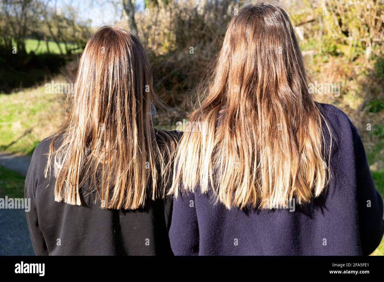 Rückansicht Hinterkopf zwei Schwestern treffen sich danach Lockdown Einschränkungen mit langen braunen Haaren gesund glänzend von hinten In Wales Großbritannien KATHY DEWITT Stockfoto