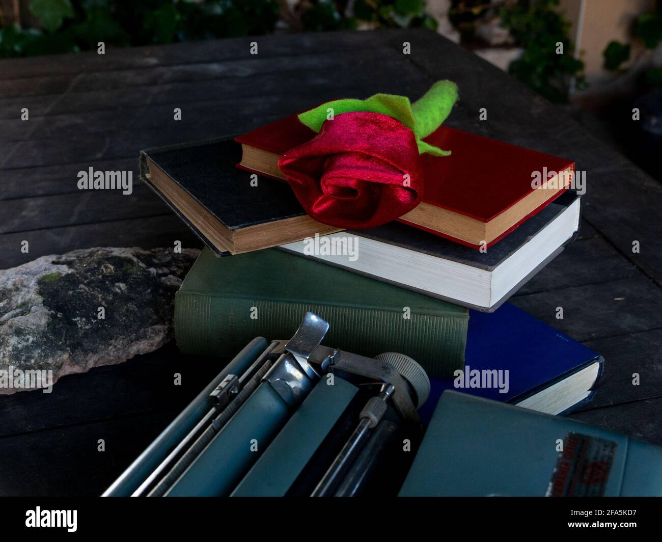Eine Rose auf einem Stapel von Büchern und Eine Schreibmaschine Stockfoto