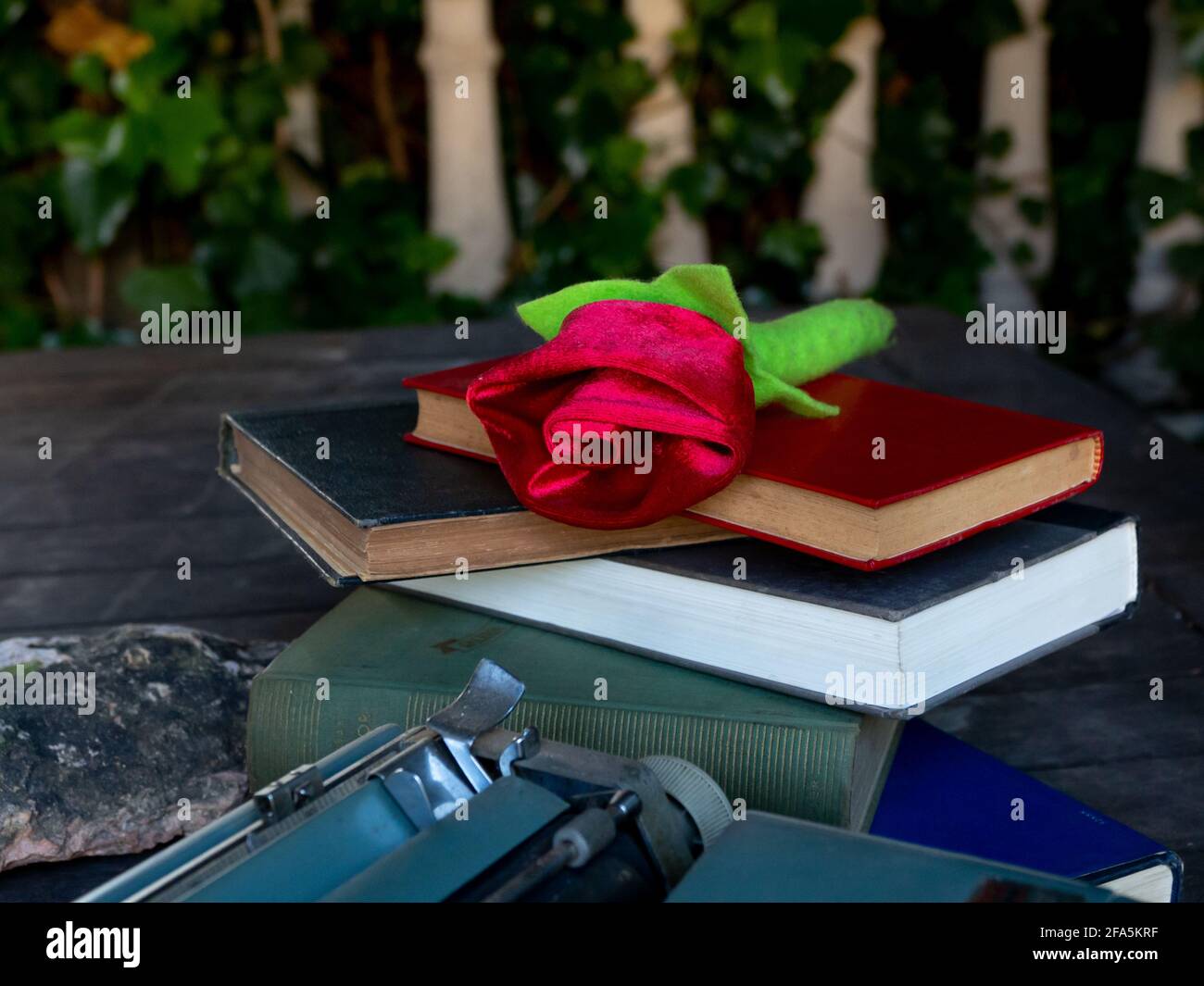 Eine Rose auf einem Stapel von Büchern und Eine Schreibmaschine Stockfoto