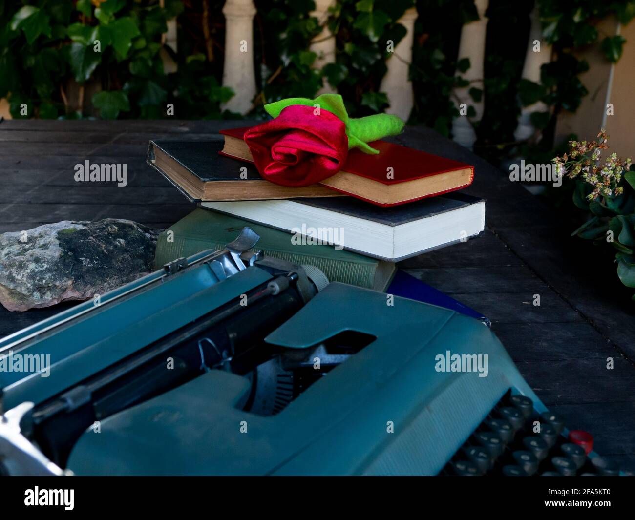 Eine Rose auf einem Stapel von Büchern und Eine Schreibmaschine Stockfoto