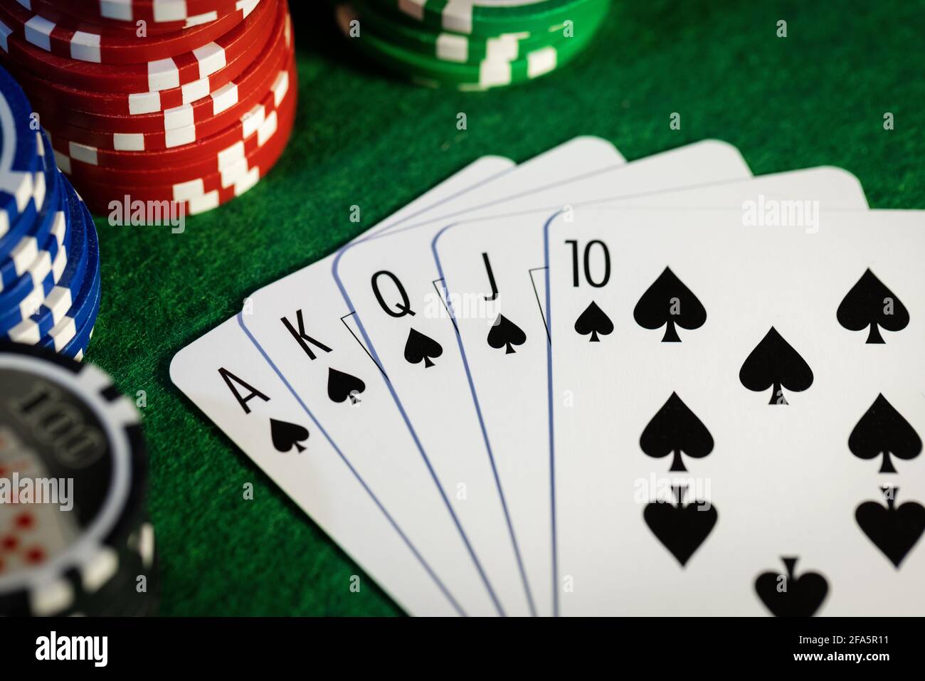 royal Flush im Pokerspiel. Karten mit Casino-Chips auf grünem Tuch Stockfoto
