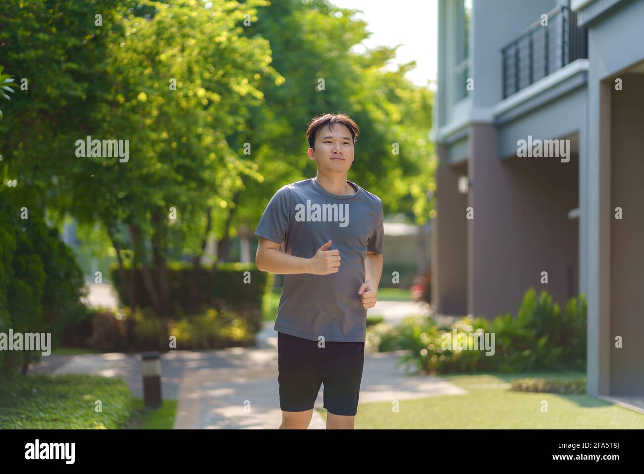 Der asiatische Mann joggt in der Nachbarschaft für die tägliche Gesundheit und das Wohlbefinden, sowohl körperlich als auch geistig, und ist ein einfaches Gegenmittel gegen den täglichen Stress und gegen Socia Stockfoto