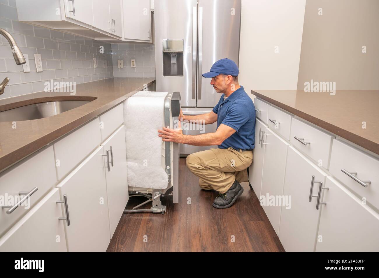 Reparaturman installiert einen Geschirrspüler in einer modernen Küche Stockfoto