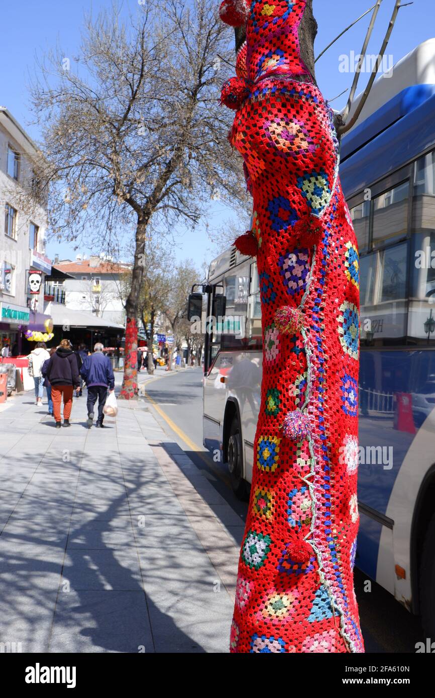 Baum gekleidet mit roter, handgestrickter Textur auf der Straße Stockfoto