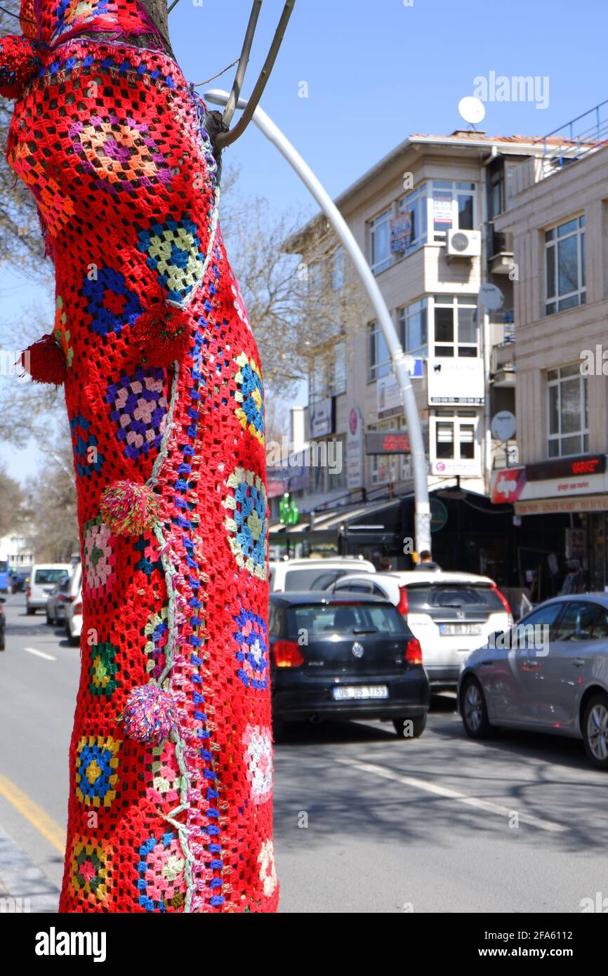 Baum gekleidet mit roter, handgestrickter Textur auf der Straße Stockfoto