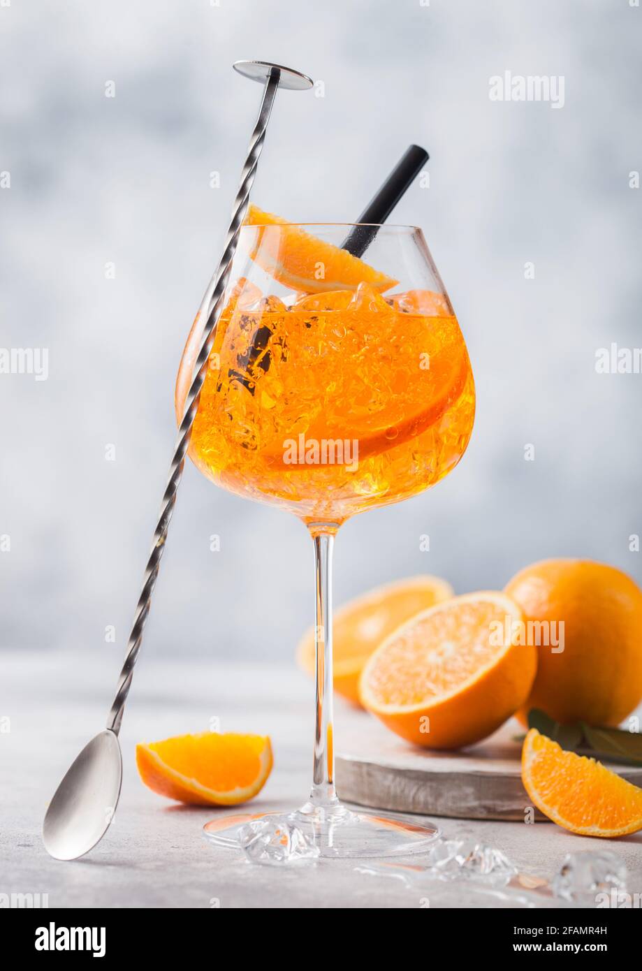 Ein Glas aperol Spritz Sommercocktail mit Orangen und Barlöffel auf hellem  Tischhintergrund. Eiswürfel und schwarzes Stroh Stockfotografie - Alamy