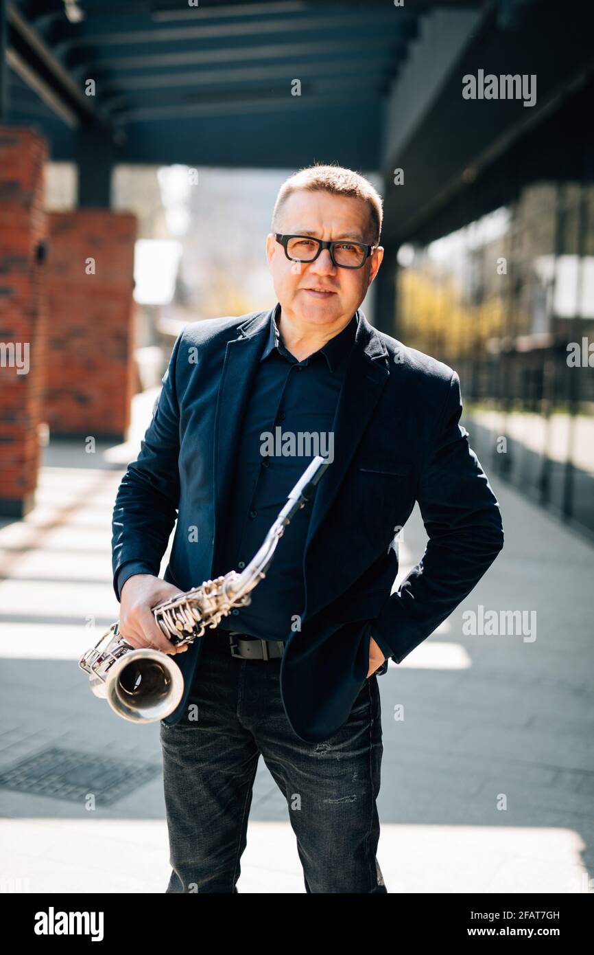 englischer Straßenmusiker mittleren Alters, der auf Saxophon spielt Stockfoto