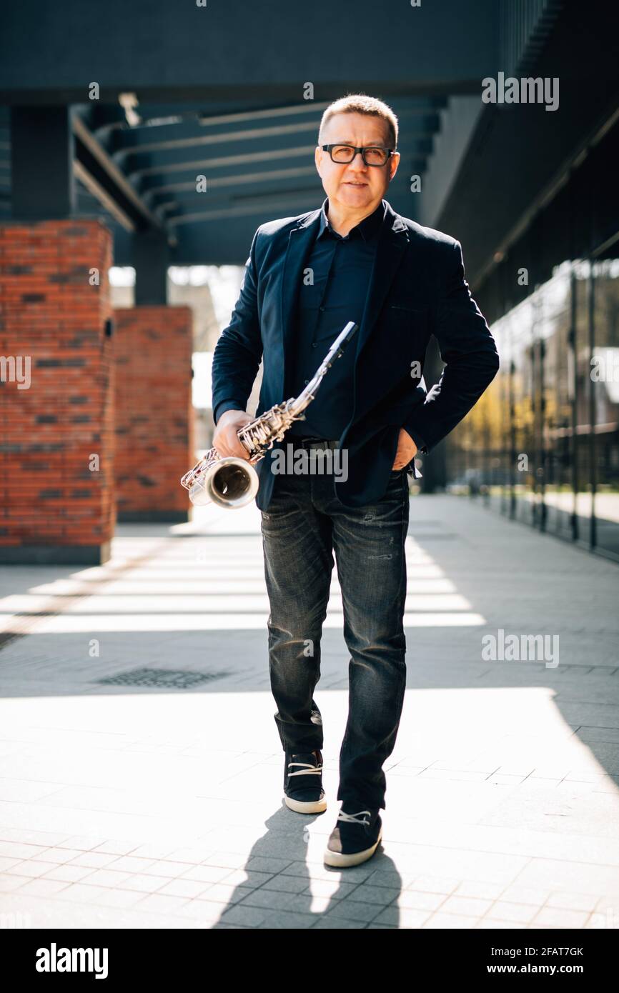 Mann mittleren Alters mit Saxophon auf urbanem Hintergrund Stockfoto