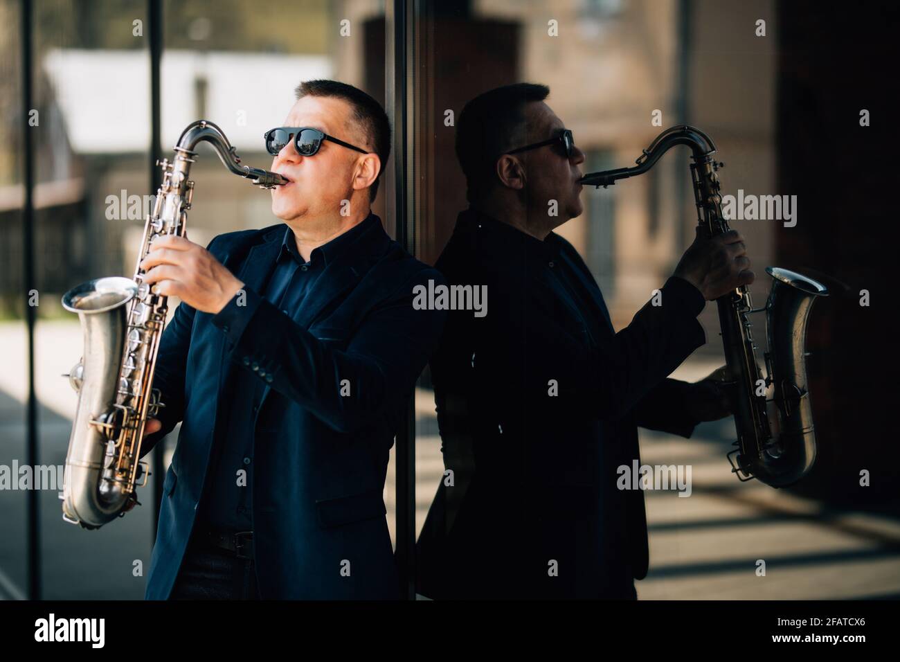 Saxophonist spielt auf der Straße ein goldenes Saxophon mit Passanten in Sicht. Frühling. Stockfoto