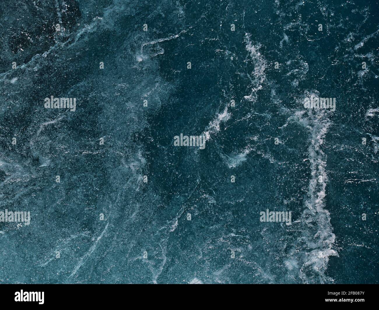 Nahaufnahme aus einem hohen Winkel des wilden Gebirgsbaches Hvítá bei den Hraunfossar-Kaskaden, Húsafell, Westisland mit dem Spray türkisfarbenem Wasser. Stockfoto