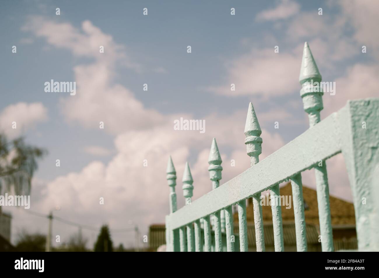 Alte vintage gestrichene Zaun auf blau bewölkten Himmel Hintergrund Stockfoto