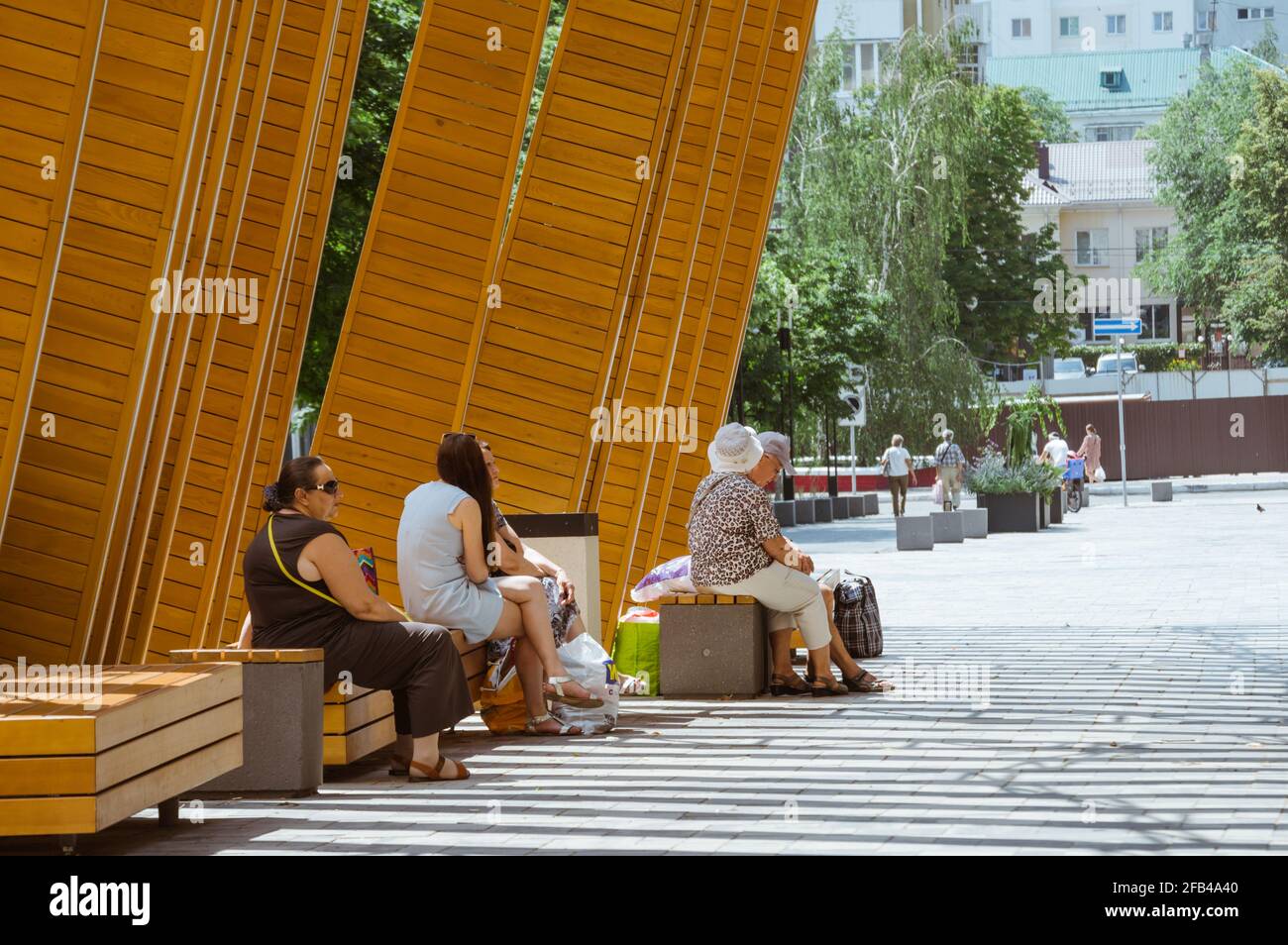 Im Sommer sitzen Menschen auf Parkbänken Stockfoto