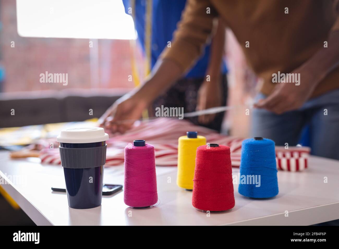 Diverse männliche und weibliche Modedesigner bei der Arbeit messen Kleidung Und Stoff Stockfoto