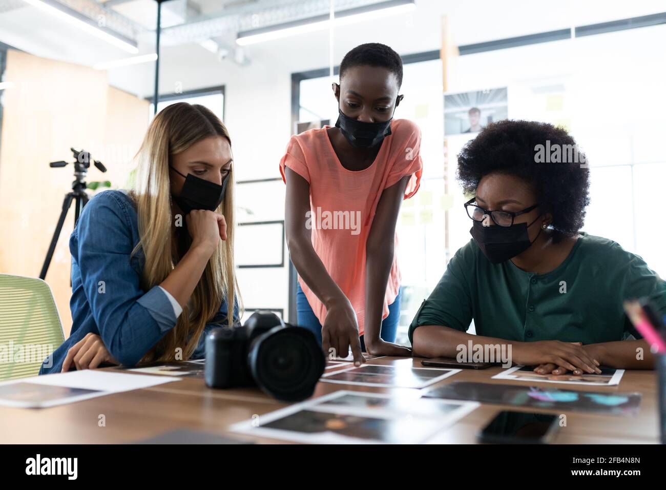 Verschiedene Gruppe von Geschäftskollegen tragen Masken Brainstorming Blick auf Fotos im Tagungsraum Stockfoto