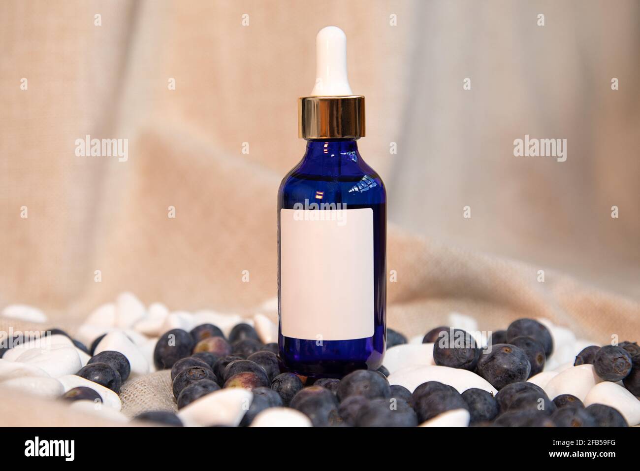 Nachbildung einer schönen Aufnahme einer blauen Glasflasche mit Pipette und Serum auf natürlichem Hintergrund. Gesichtspflege, Feuchtigkeitscreme-Konzept. Modisch Stockfoto