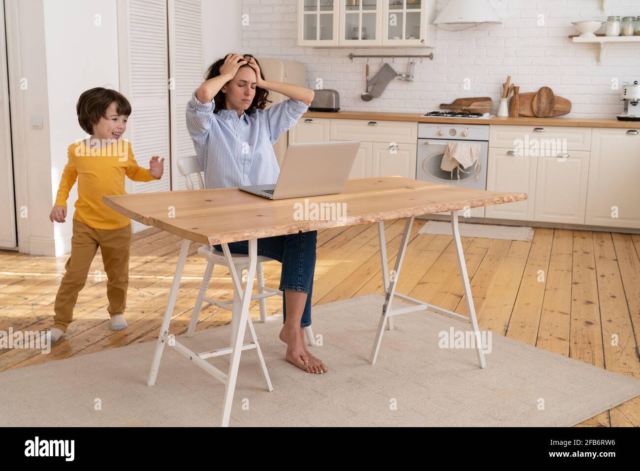 Laute Sohn stören beschäftigt Mutter Arbeit Remote von Home Office Während der covid-19-Quarantänesperre Stockfoto