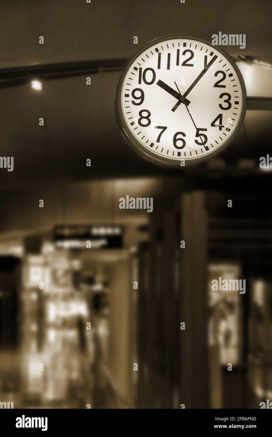 Die Uhr hängt über einem leeren Korridor im Flughafen. Stockfoto