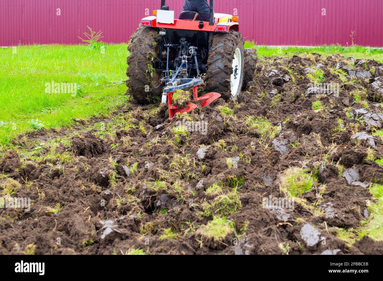 Ein Traktor mit Pflug pflügt im Frühjahr ein landwirtschaftliches Feld zum Anpflanzen von Kartoffeln. Pflügen des Landes. Stockfoto