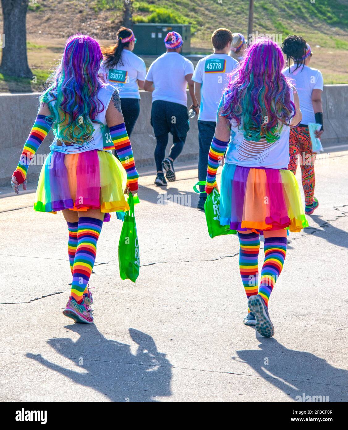 4-6-2019 Tulsa - zwei Frauen, die am Tulsa Color Run teilnehmen, gehen mit langen, regenbogenfarbenen Haaren, Regenbogenstreifen-Tutus und Socken von der Kamera weg Stockfoto