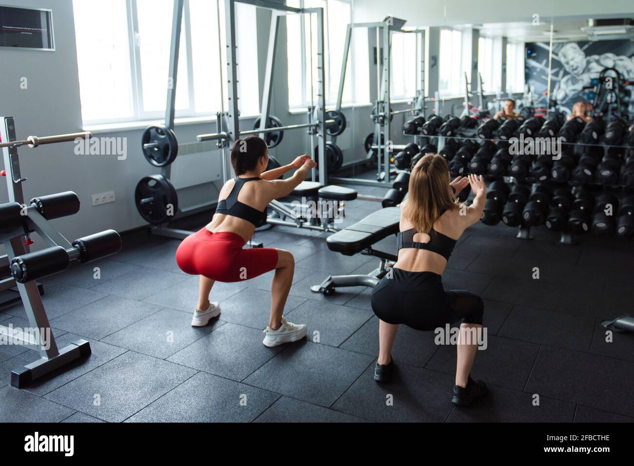 Ruckansicht Von Fit Und Gesunde Junge Frauen In Sportbekleidung Tun Kniebeugen Ubungen In Hellen Fitnessraum Zwei Freundinnen Mit Dunklen Haaren Trainingsbeine Indoo Stockfotografie Alamy
