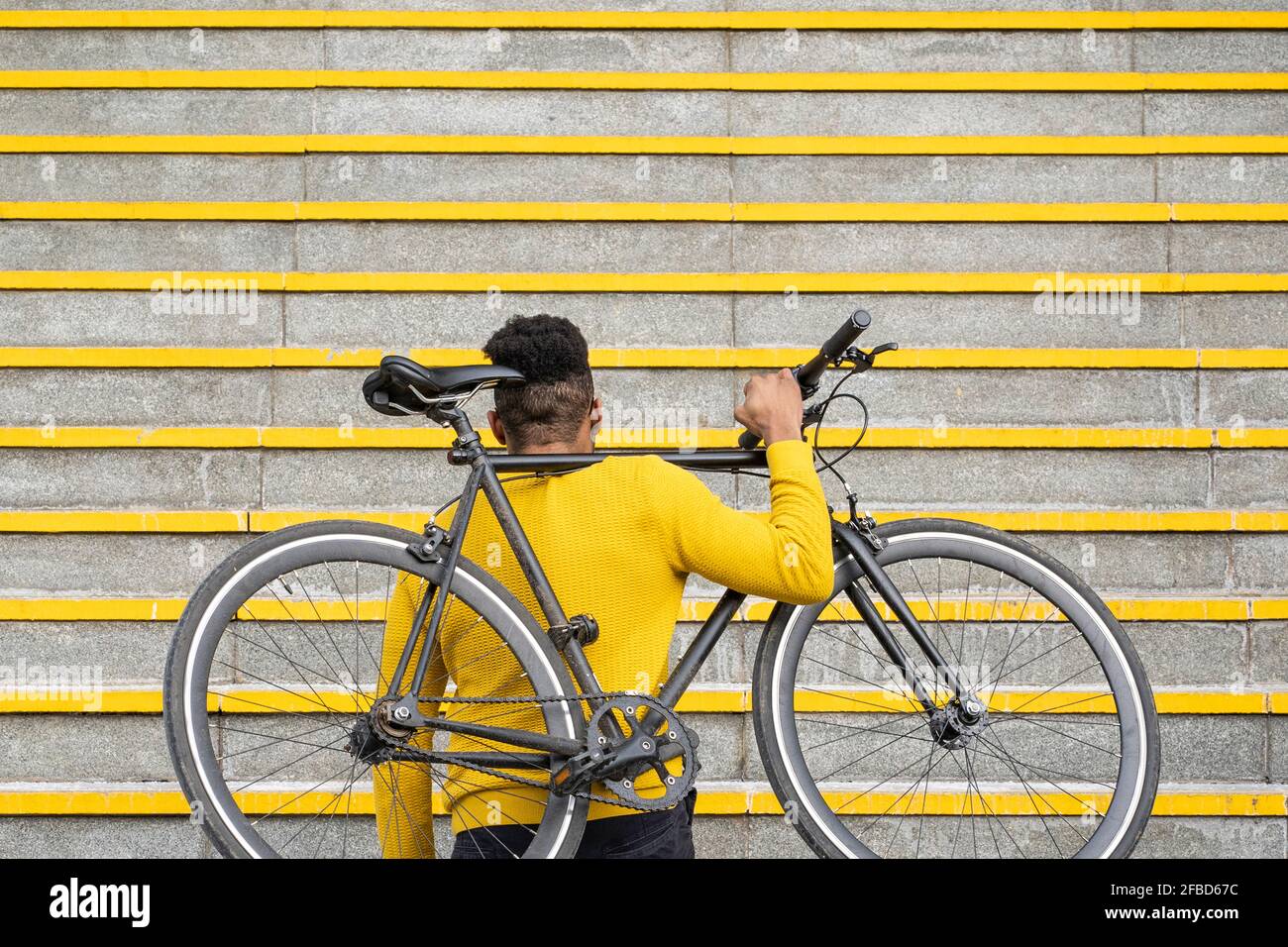Mann, der Fahrrad auf der Schulter auf der Treppe trägt Stockfoto