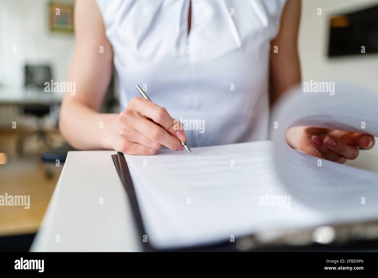 Geschäftsfrau unterzeichnet Vertrag im Büro Stockfoto