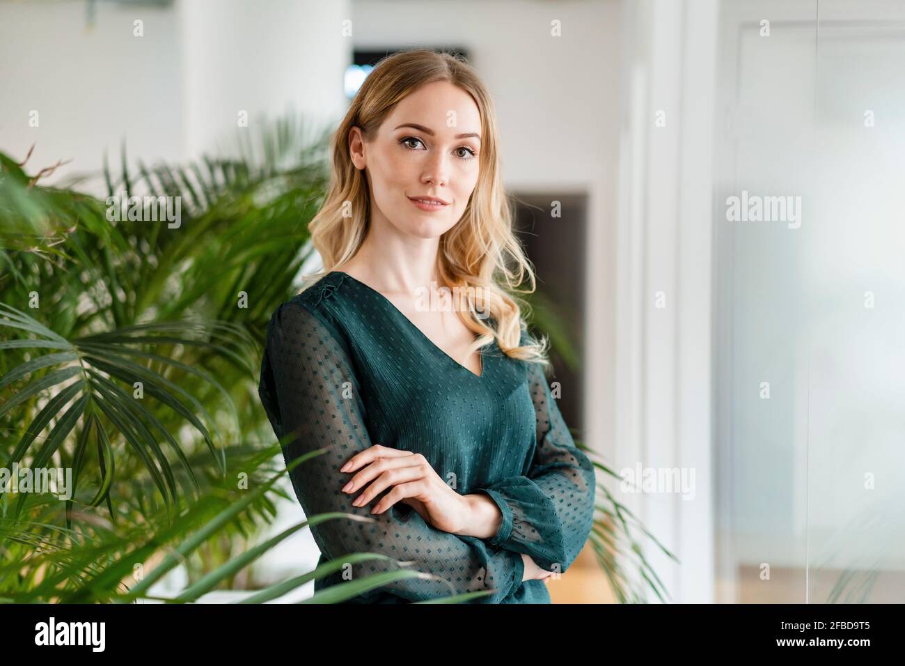 Unternehmerin mit gekreuzten Armen im Büro stehend Stockfoto