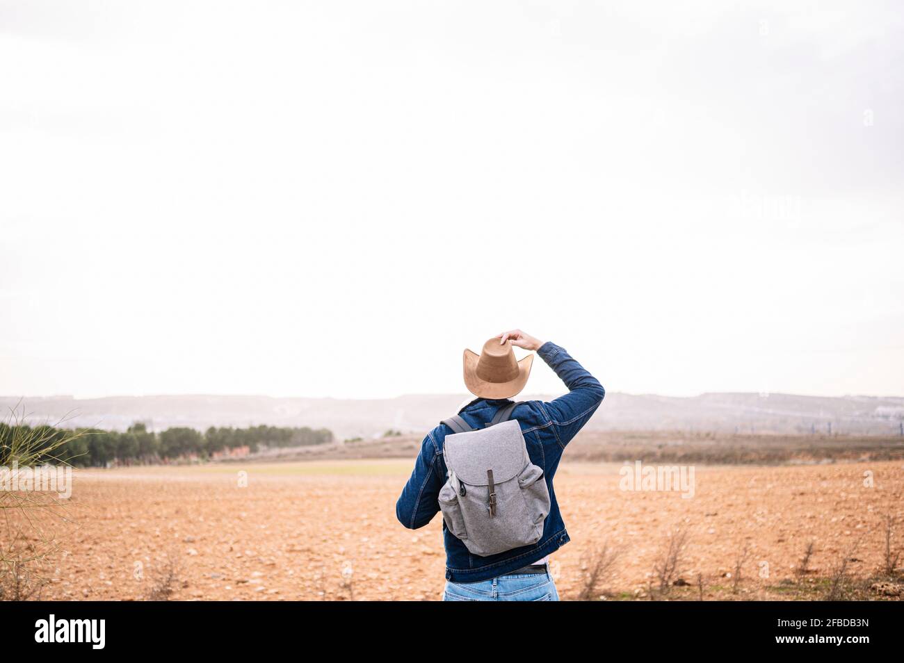 Reifer Mann Anpassung Hut beim Blick auf Landschaft während des Urlaubs Stockfoto