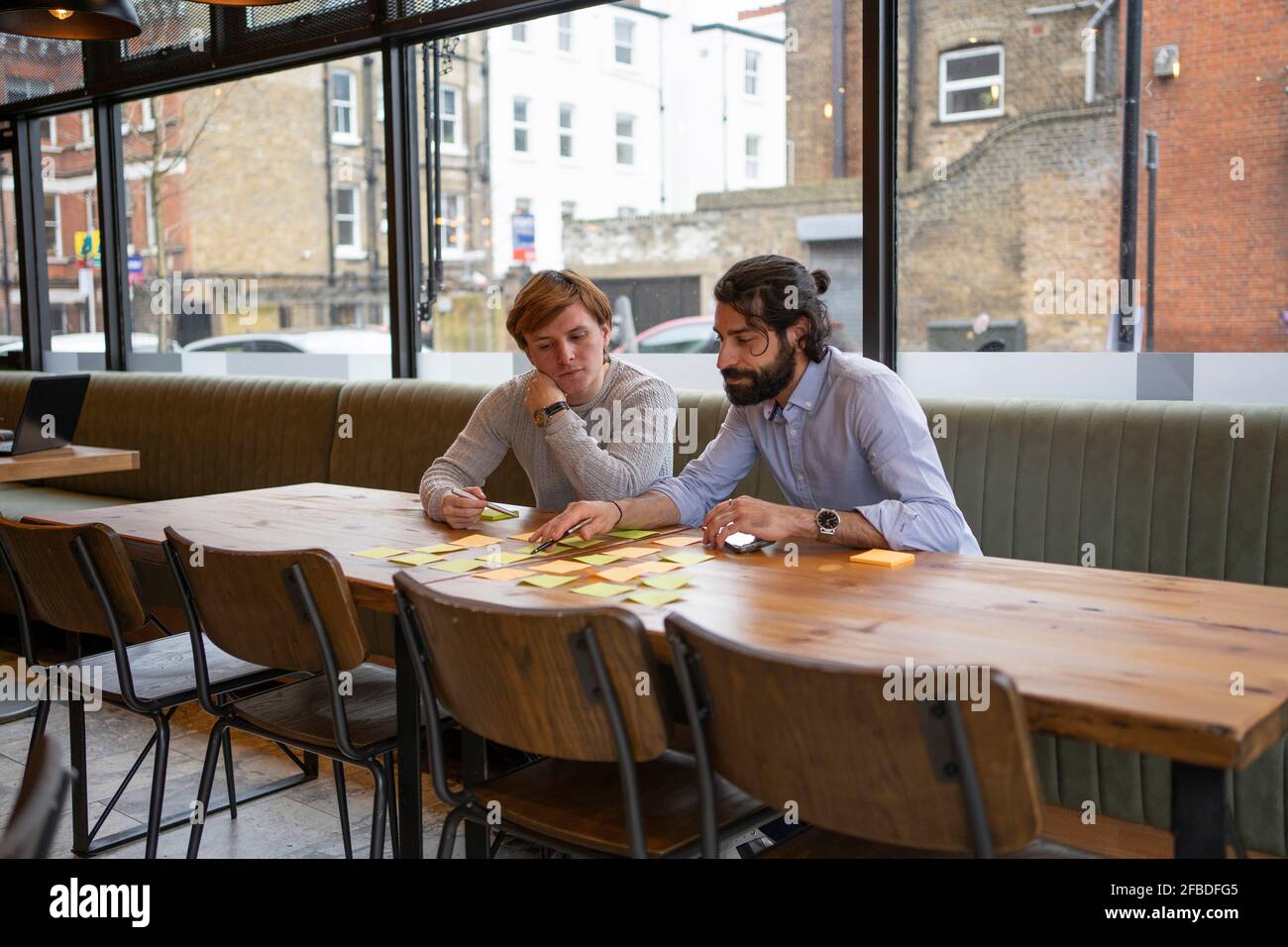 Ein Geschäftsmann hat einen männlichen Kollegen beim Brainstorming am Schreibtisch im Büro sitzend Stockfoto