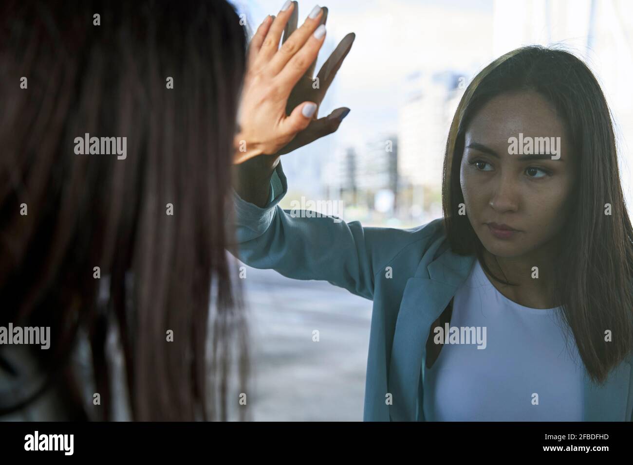 Weibliche Unternehmerin, die auf Selbstreflexion an der Glaswand schaut Stockfoto