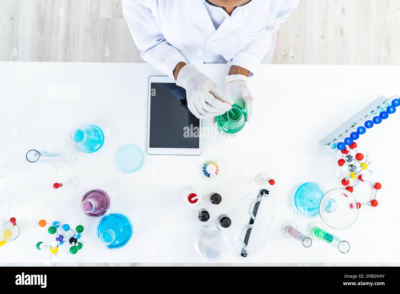 Forscherin testet Flüssigkeit in Kolben auf dem Tisch im Labor Stockfoto