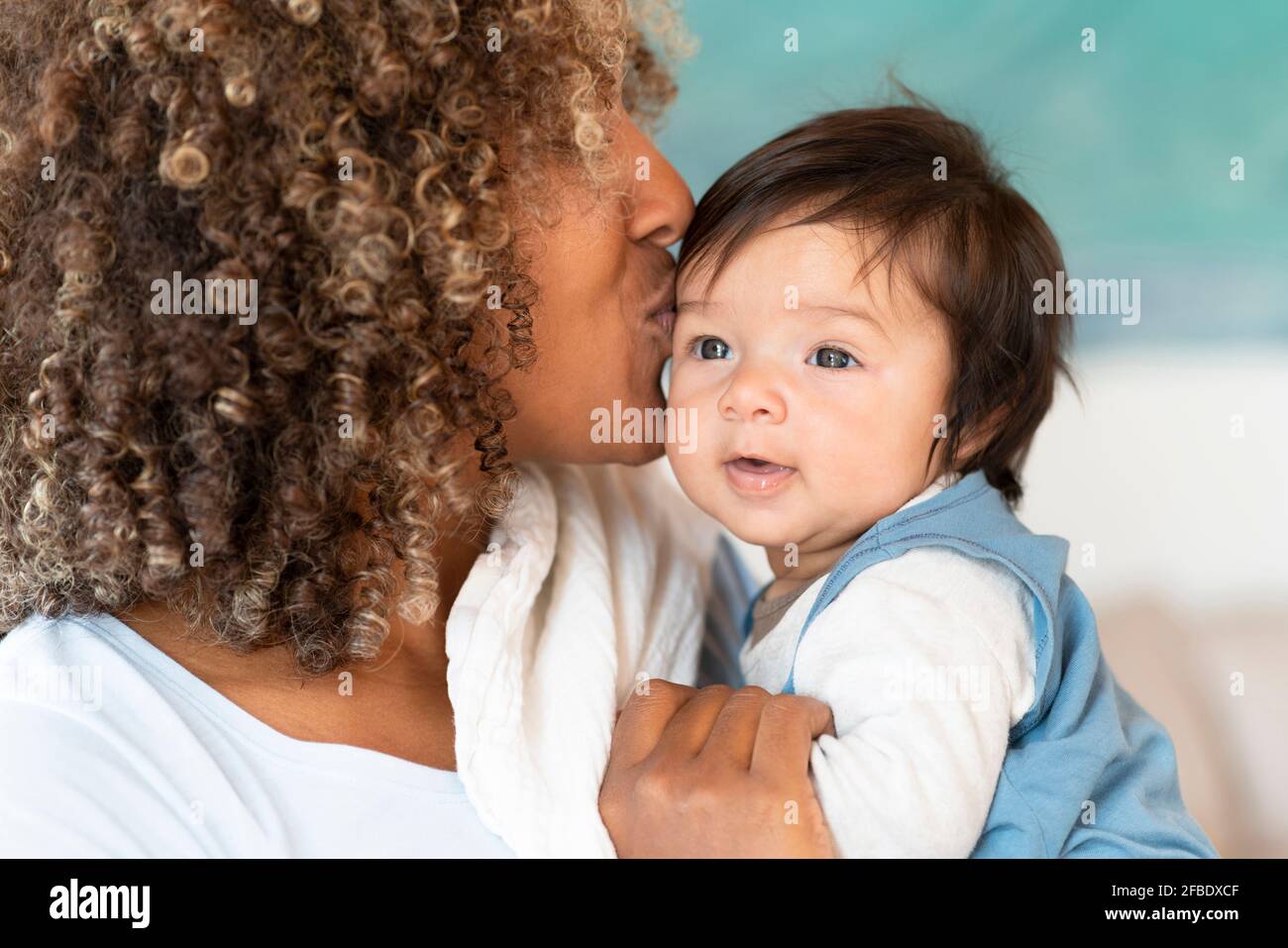 Mutter küsst niedliches Baby auf der Stirn zu Hause Stockfoto